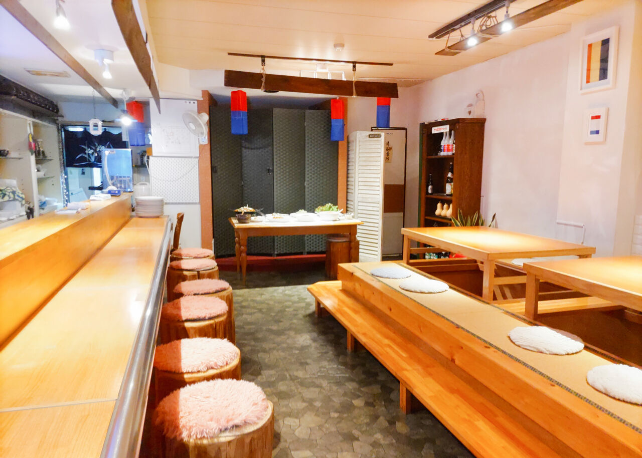 明るいマポナルの店内。木のカウンターと丸い椅子、掘りごたつのテーブル席