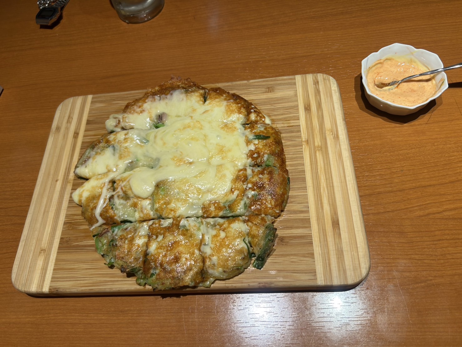 木のボードに盛られたチーズのかかった焼き料理